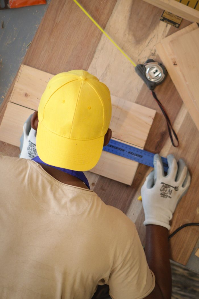 A man working with precision measuring wood in Blantyre, Malawi for carpentry.